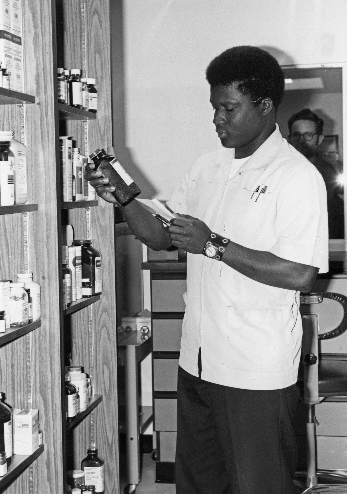 A man in a pharmacy examines a bottle.