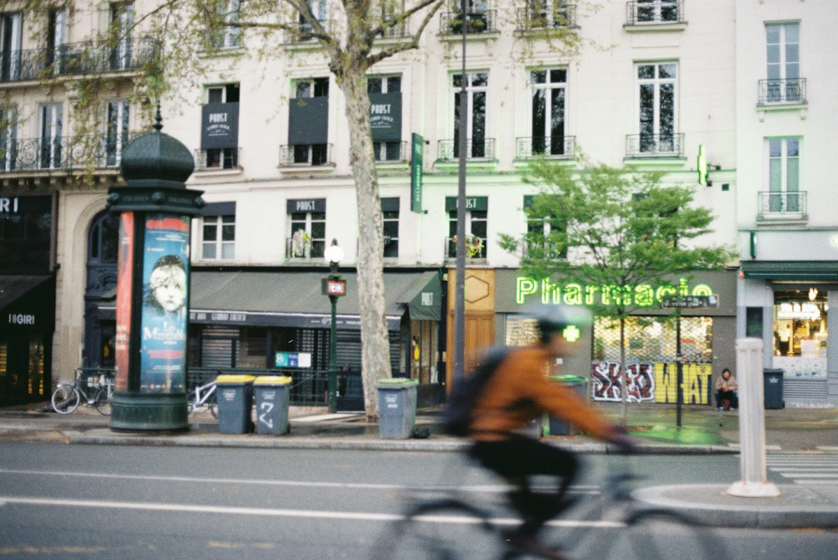 Cyclist passes a pharmacy in an urban setting