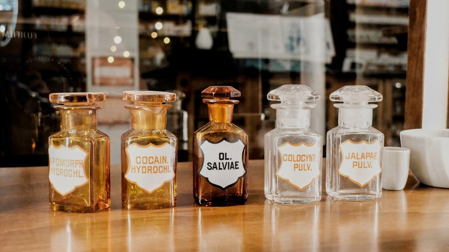 Antique pharmacy bottles with labels on a wooden counter.