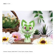 Completed Bandai Sprigatito Pokémon model kit displayed with flowers and green plants